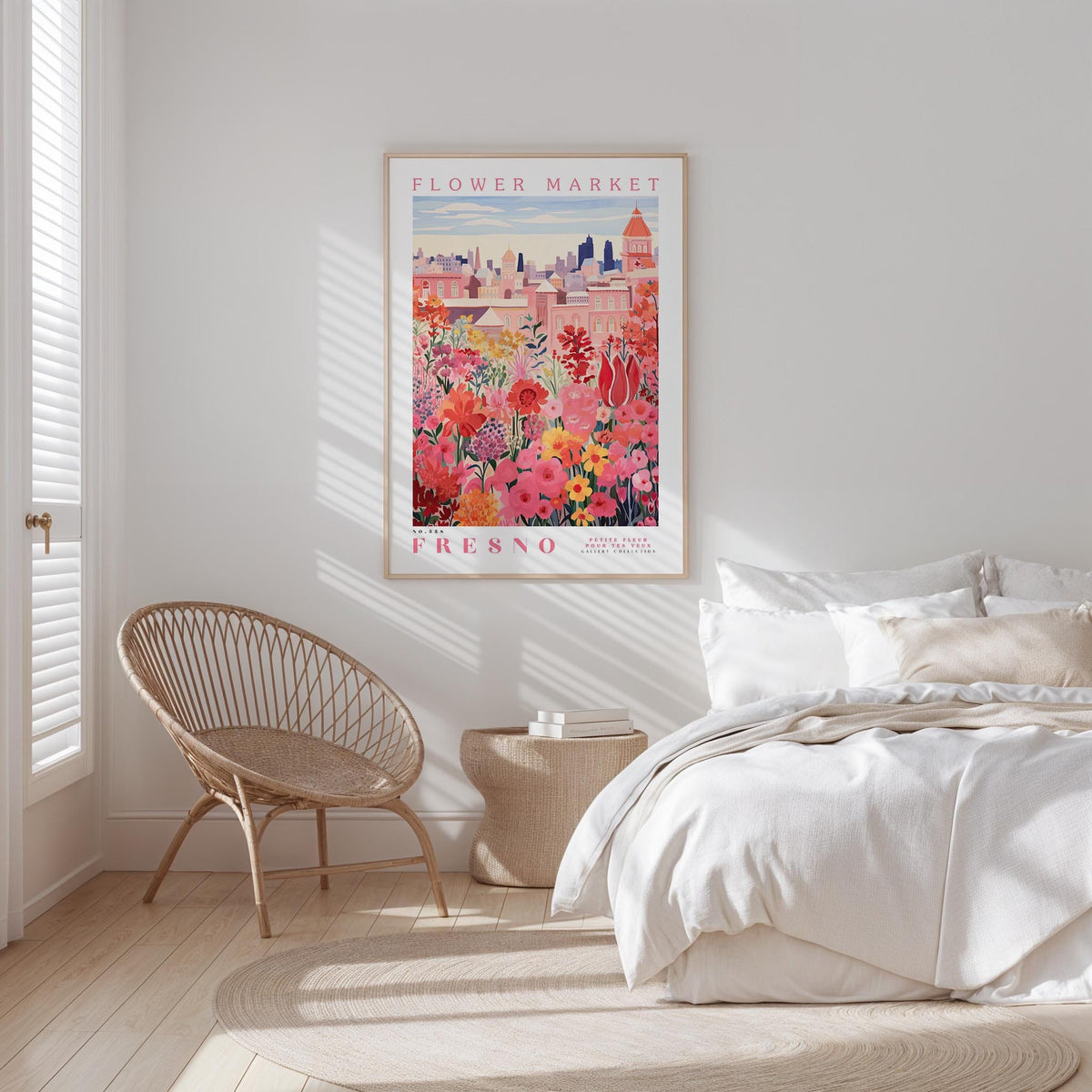 a bedroom with a bed, a woven chair, and a framed poster of a cityscape with flowers hanging on the wall.