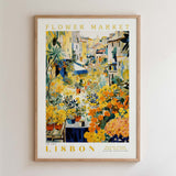 The image is a framed poster depicting a vibrant and colorful flower market in Lisbon, Portugal.