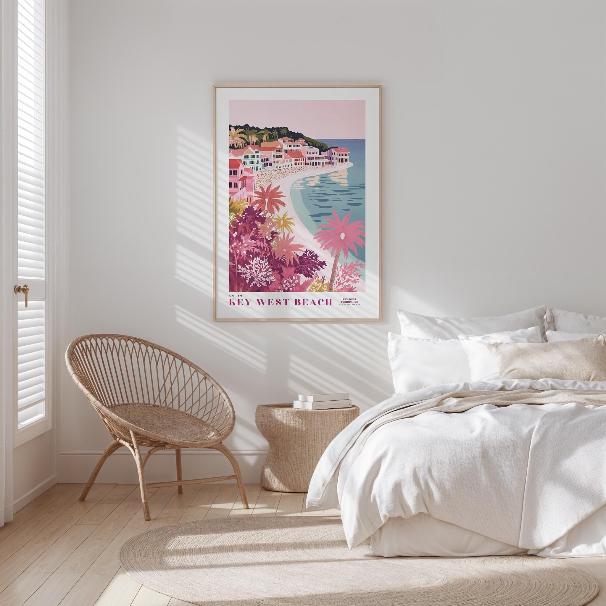 a bedroom with a large poster of a beach scene hanging on the wall, a wicker chair, and a bed with white bedding.