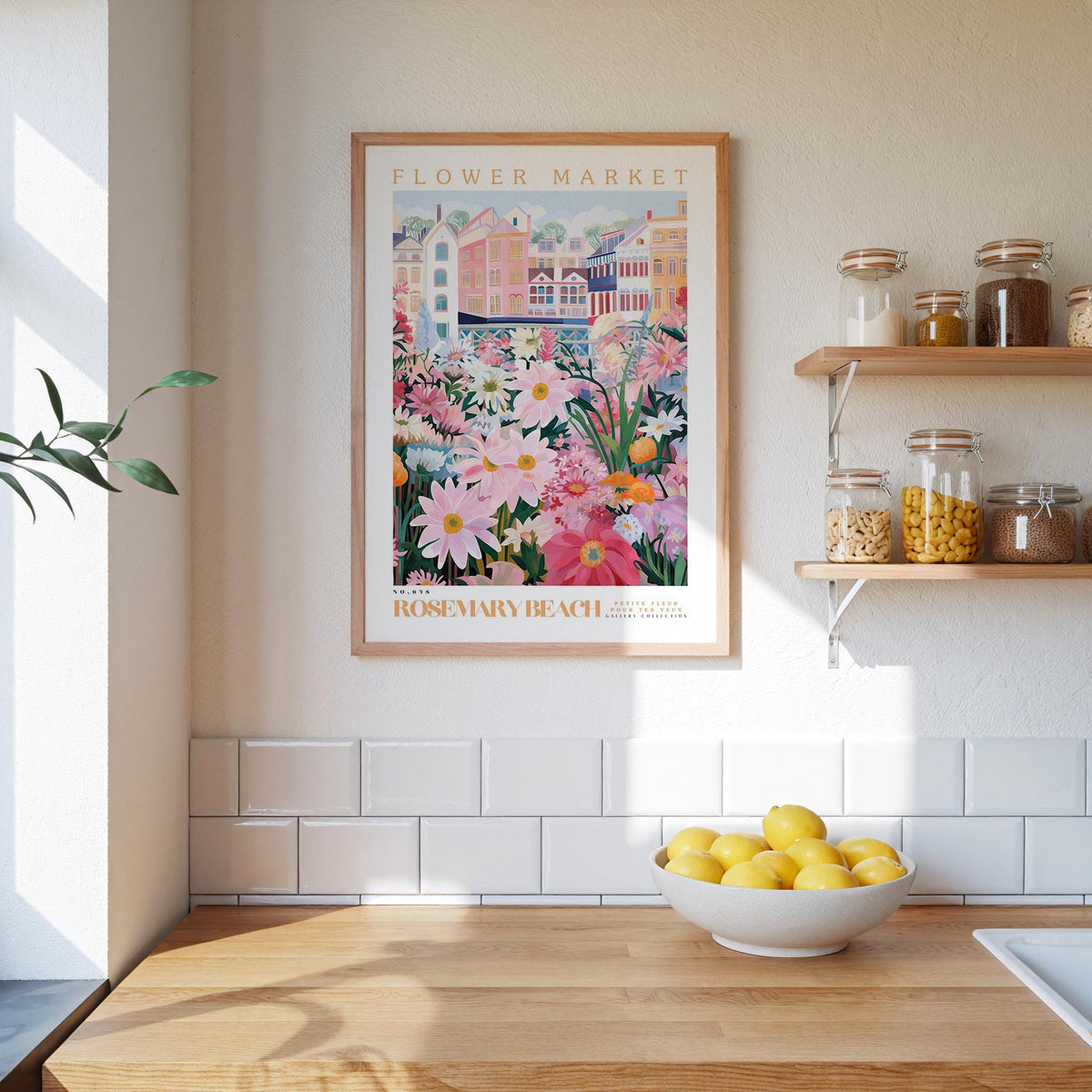 a kitchen scene with a framed poster of a colorful floral market on the wall above a wooden countertop with a bowl of lemons.