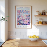 a kitchen counter with a bowl of lemons, a framed poster of a flower market in Perth, and a shelf with jars and containers.