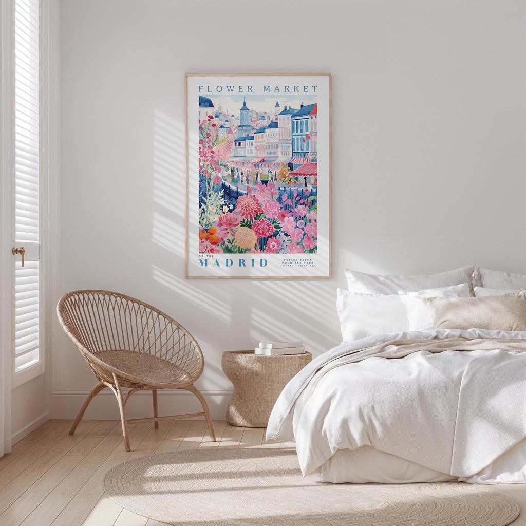 a bedroom with a large poster of a colorful cityscape hanging on the wall, a woven chair, and a bed with white bedding.