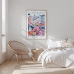 a bedroom with a large poster of a colorful cityscape hanging on the wall, a woven chair, and a bed with white bedding.