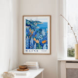 a framed poster of a coastal landscape with a lighthouse, hanging on a wall in a room with a white table and a window.