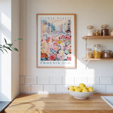 a framed poster of a colorful cityscape with flowers hanging on a wall above a wooden countertop with a bowl of lemons.