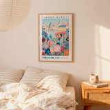 a bedroom setting with a framed poster of a colorful floral scene hanging on the wall above a bed with striped pillows.