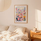 a bedroom with a bed, a nightstand, and a framed poster of a cityscape with flowers hanging on the wall.