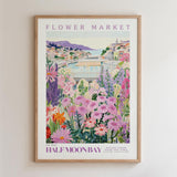 The image is a framed poster depicting a vibrant and colorful flower market in Half Moon Bay, California.