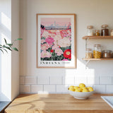 a framed poster of a field of flowers with a city skyline in the background, hanging on a wall above a kitchen counter with a bowl of lemons and other kitchen items.