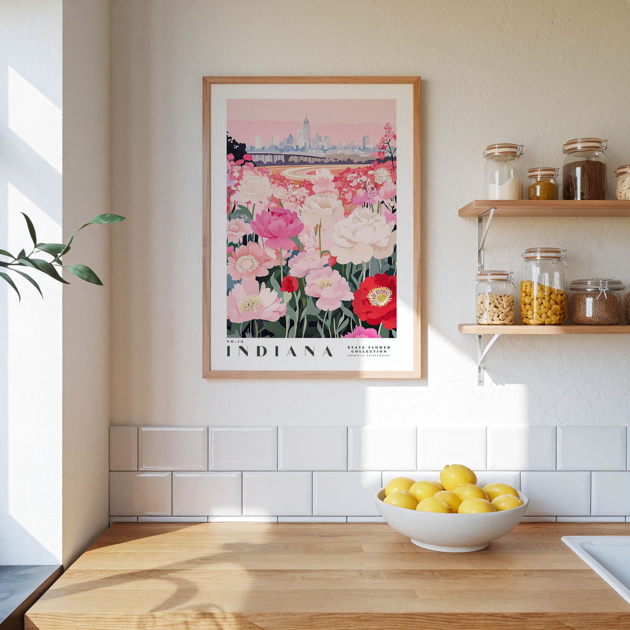 a framed poster of a field of flowers with a city skyline in the background, hanging on a wall above a kitchen counter with a bowl of lemons and other kitchen items.