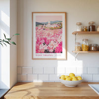 a kitchen counter with a bowl of lemons, a framed poster of a pink flower field, and a shelf with jars and containers.