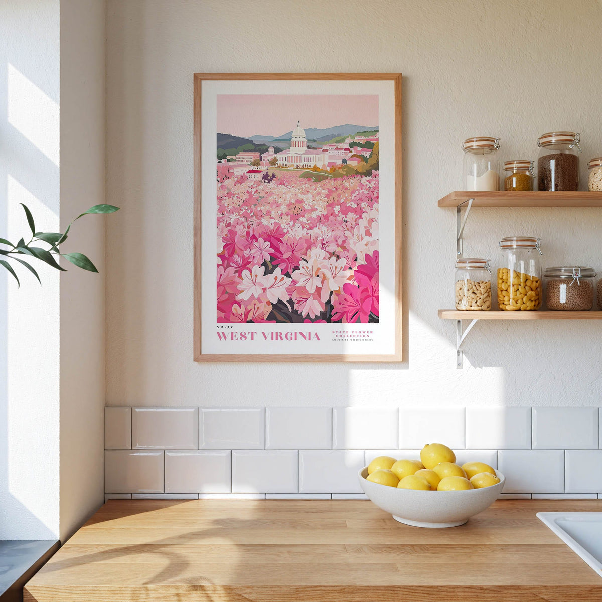 a kitchen counter with a bowl of lemons, a framed poster of a pink flower field, and a shelf with jars and containers.