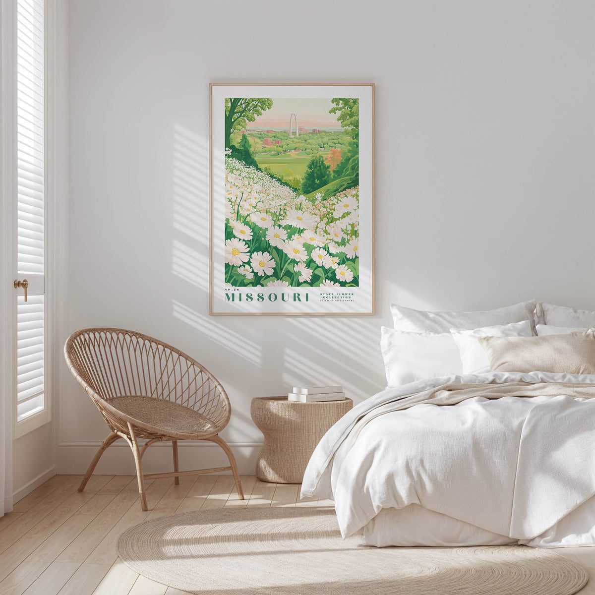 a serene bedroom scene with a large framed poster of a field of flowers hanging on the wall, a woven chair, and a neatly made bed with white bedding.