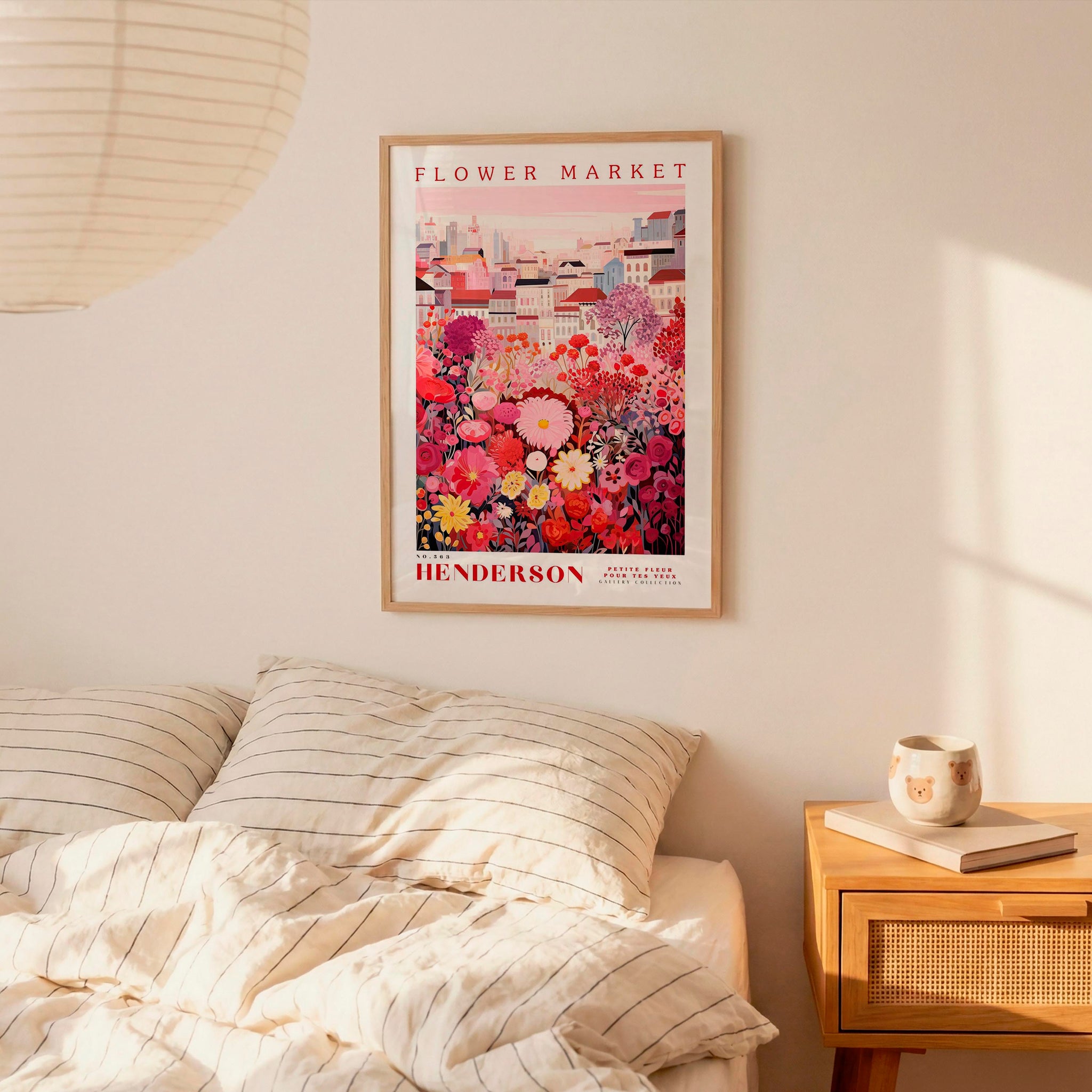 a bedroom scene with a framed poster of a colorful floral arrangement hanging on the wall above a bed with striped pillows.