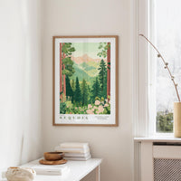 a framed poster of a lush forest scene with mountains in the background, hanging on a wall in a room with a white table and a window.