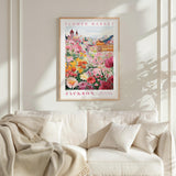 a framed poster of a vibrant flower market in Jackson, with a variety of colorful flowers and buildings in the background.
