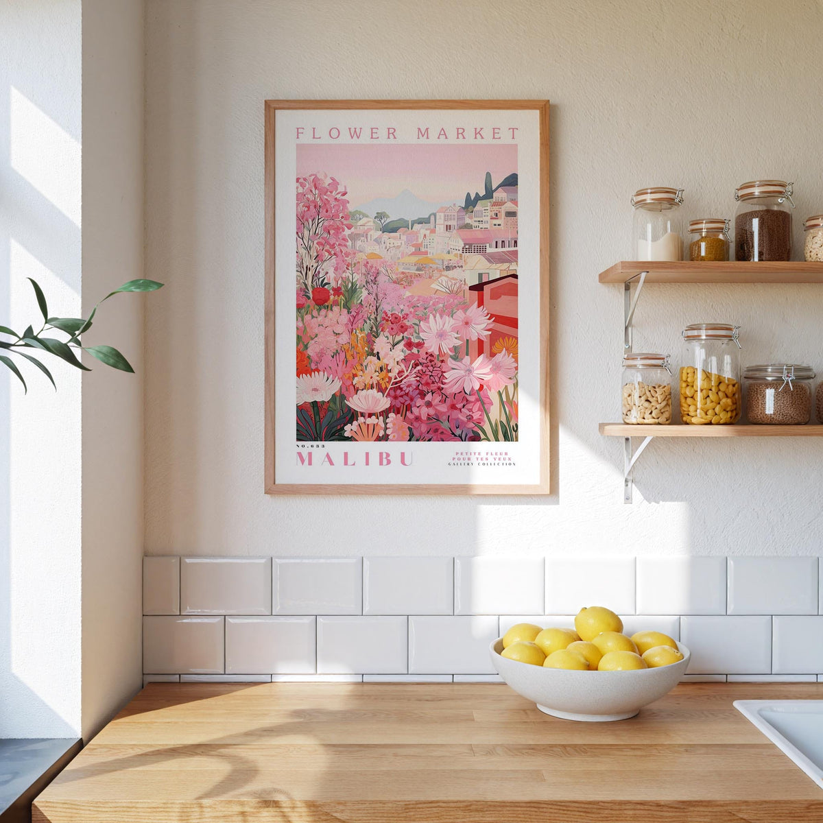 a framed poster of a colorful floral scene hanging on a wall above a wooden countertop with a bowl of lemons.