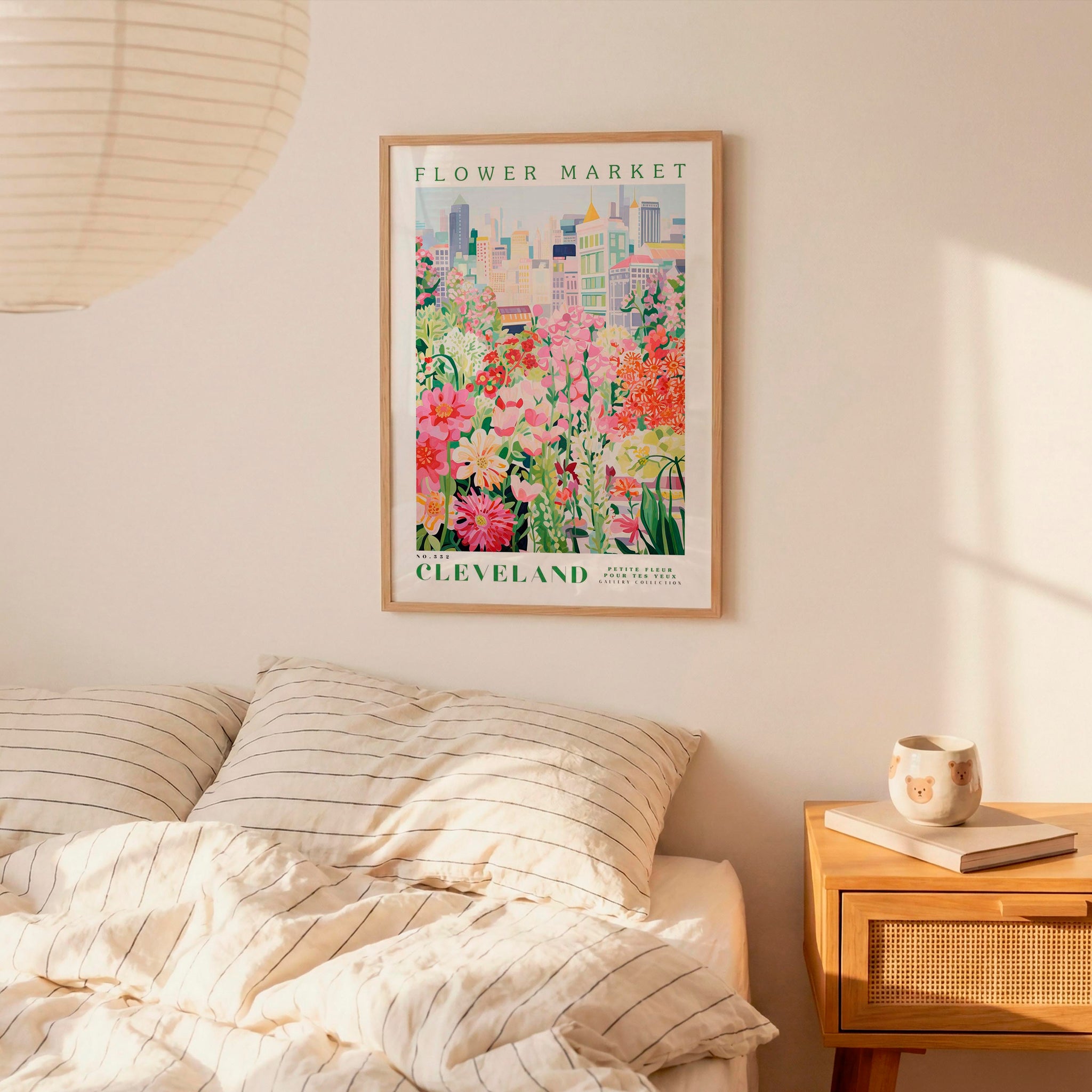 a framed poster of a colorful garden scene hanging on a wall above a bed with striped pillows.