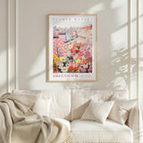 a poster of a flower market in Greenwich, with a cityscape in the background. The poster is hung on a wall above a white couch, which has a blanket draped over it.