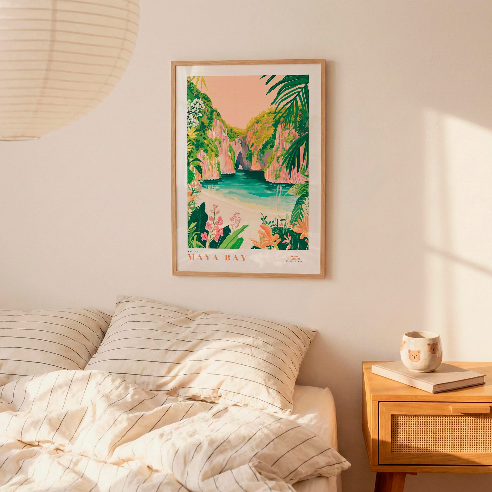 a bedroom with a framed poster of a tropical island landscape hanging on the wall above a bed with striped bedding.