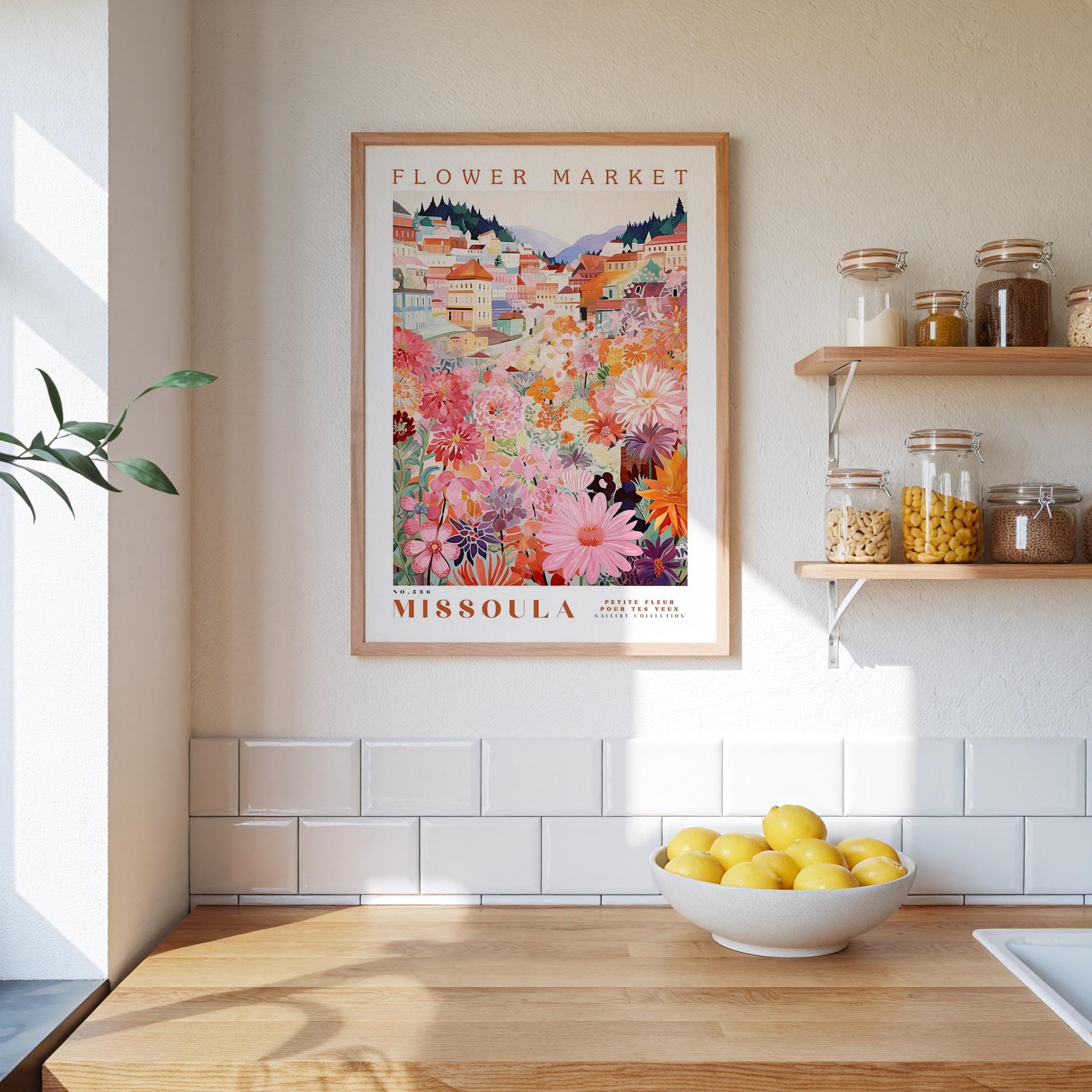 a kitchen scene with a framed poster of a flower market in Missoula, Montana, hanging on the wall above a wooden counter. The poster displays a colorful illustration of a flower market with various flowers and plants. On the counter, there is a bowl of lemons and a plant, adding a touch of greenery to the scene.