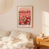a bedroom setting with a framed poster of a cityscape hanging on the wall above a bed with striped pillows.