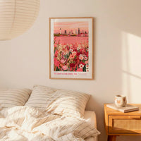 a bedroom setting with a framed poster of a cityscape hanging on the wall above a bed with striped pillows.