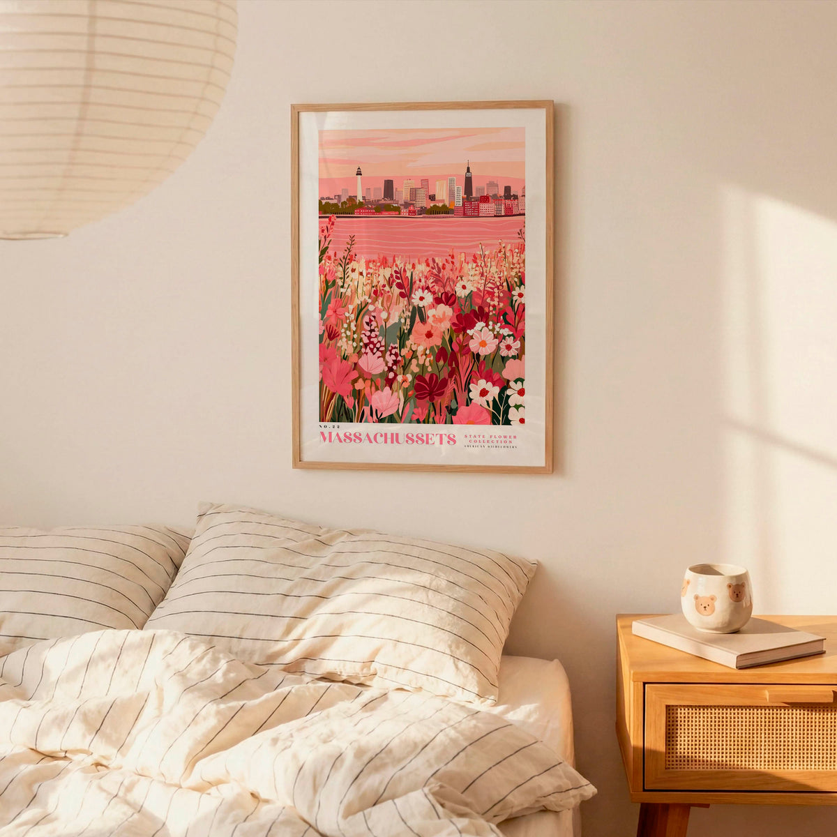a bedroom setting with a framed poster of a cityscape hanging on the wall above a bed with striped pillows.