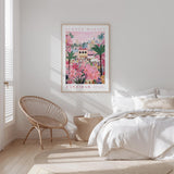 a bedroom with a large poster of a tropical flower market hanging on the wall, a woven chair, and a bed with white bedding.