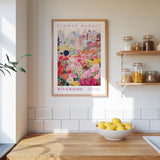 a kitchen scene with a framed poster of a flower market on the wall, a wooden counter with a bowl of lemons, and shelves with jars and containers.