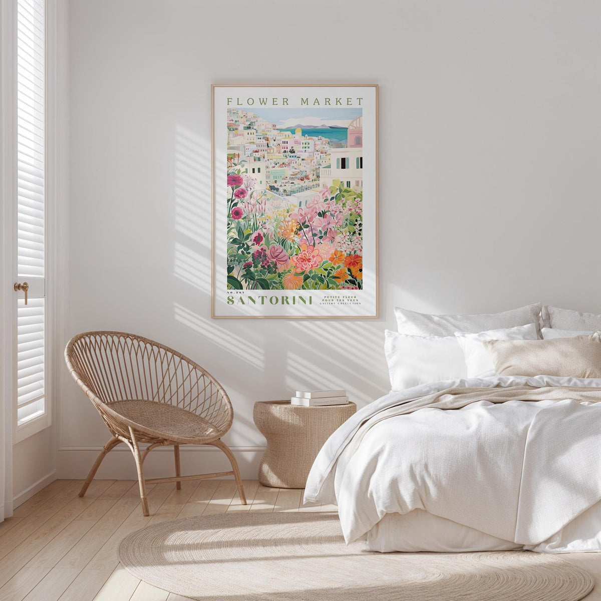 a bedroom with a bed, a woven chair, and a framed poster of a flower market in Santorini hanging on the wall.