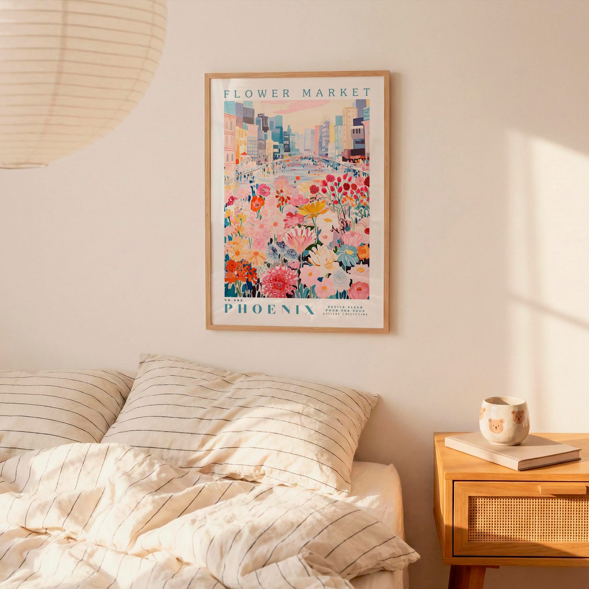 a bedroom scene with a framed poster of a colorful floral scene hanging on the wall above a bed with striped pillows.