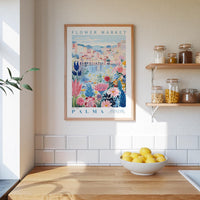 a kitchen scene with a framed poster of a colorful floral design hanging on the wall above a wooden countertop with a bowl of lemons.