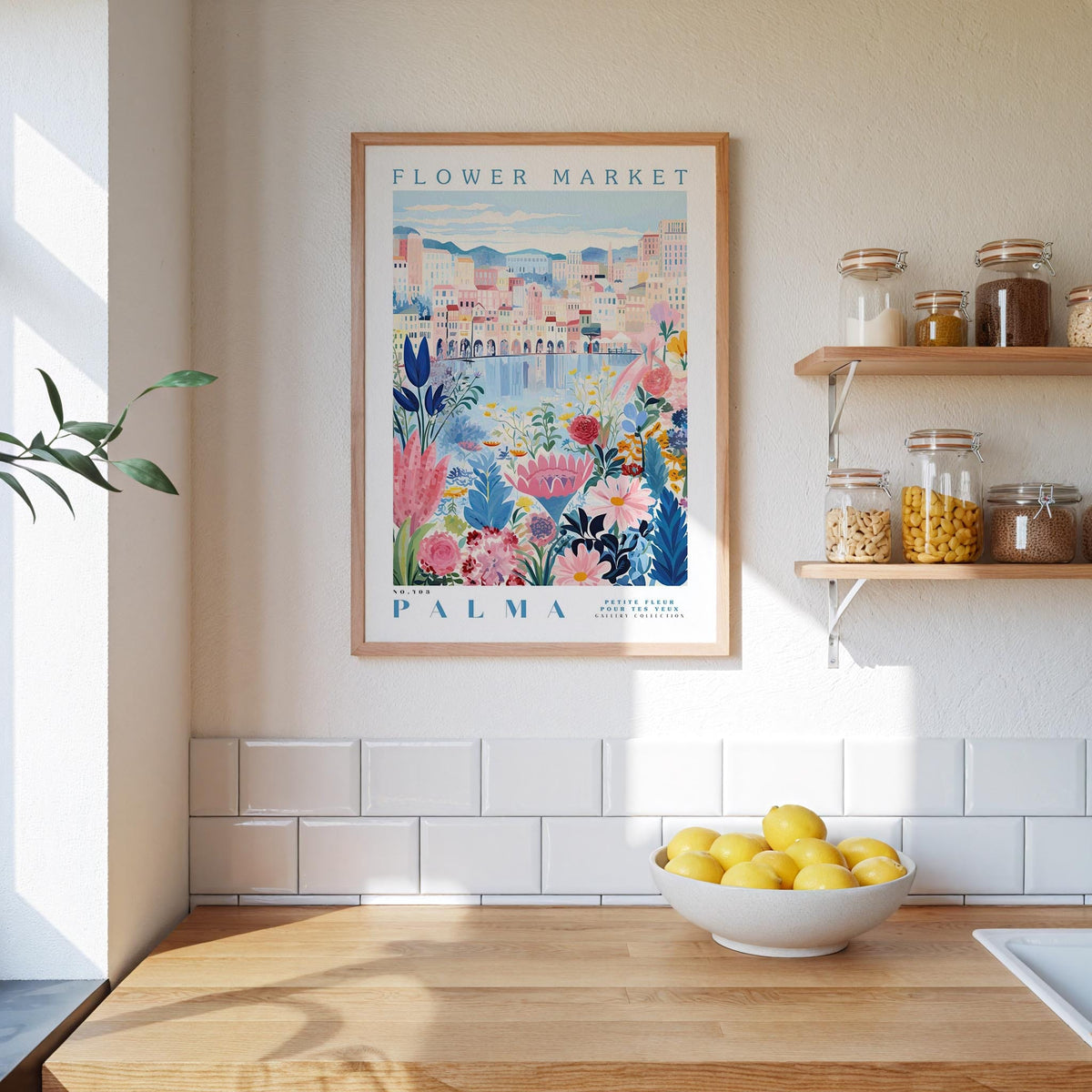 a kitchen scene with a framed poster of a colorful floral design hanging on the wall above a wooden countertop with a bowl of lemons.