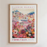 The image is a framed poster depicting a vibrant and colorful flower market in Carmel Valley, France.