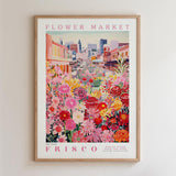 The image is a framed poster depicting a vibrant and colorful street scene with a variety of flowers and plants.