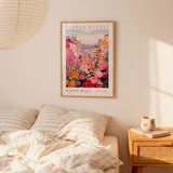 a bedroom scene with a framed poster of a colorful floral scene hanging on the wall above a bed with striped pillows.