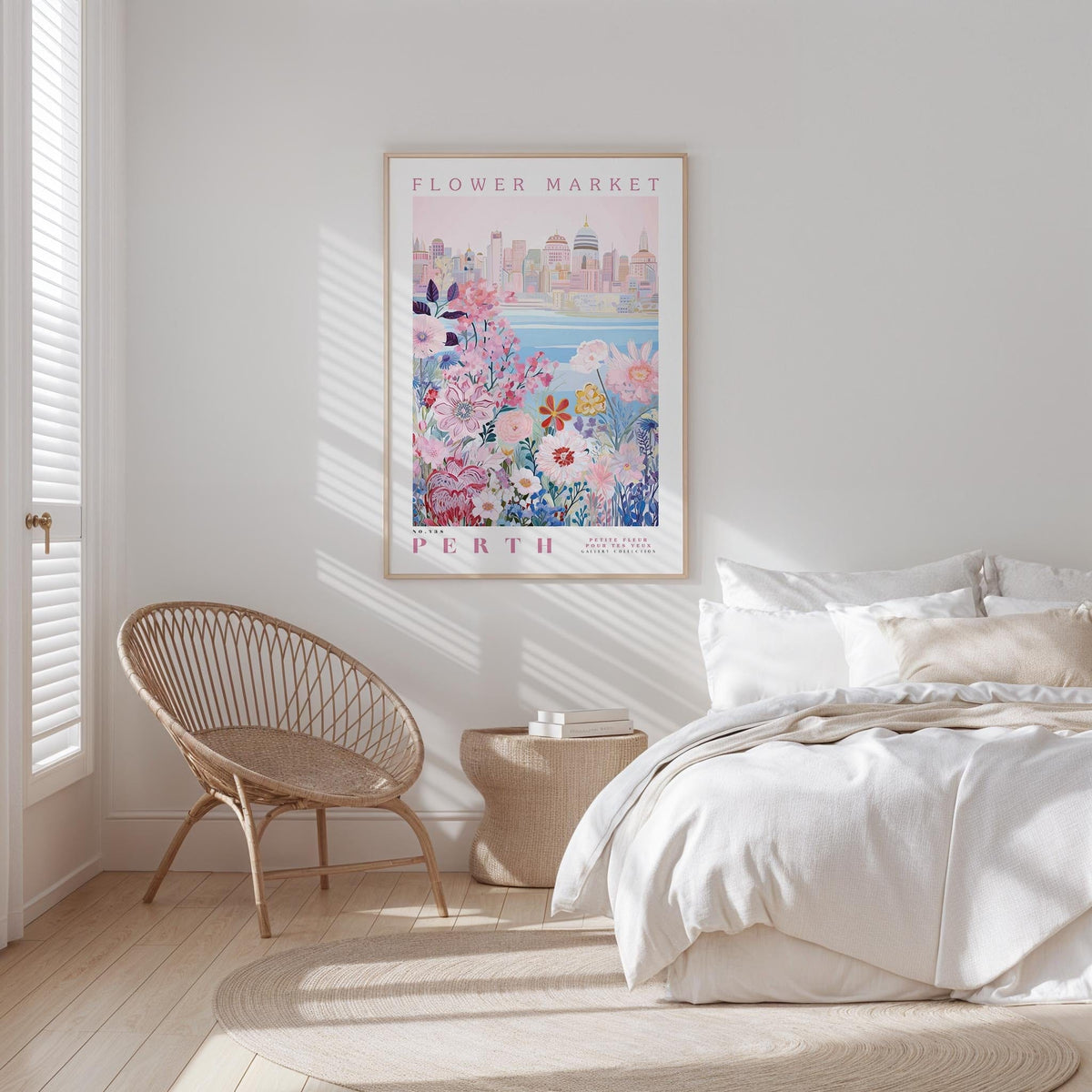 a bedroom with a bed, a woven chair, and a framed poster of a cityscape with flowers hanging on the wall.