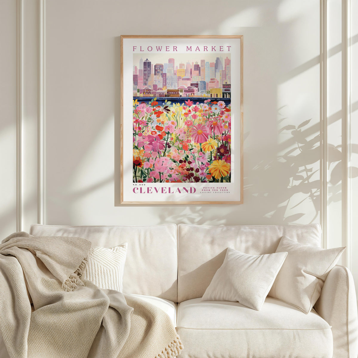 a framed poster of a cityscape with a field of colorful flowers in the foreground, hanging on a wall above a white couch.