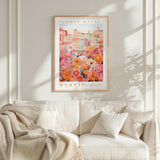 a cozy living room with a white sofa and a framed poster of a vibrant floral scene hanging on the wall above it.
