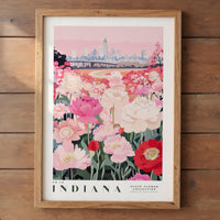 A framed poster depicting a vibrant field of pink and white flowers, with a city skyline in the background.