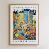 The image is a framed poster depicting a colorful and vibrant flower market scene with various flowers and buildings.