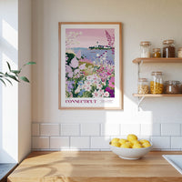 a framed poster of a garden scene with flowers hanging on a wall above a wooden table with a bowl of lemons.