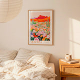 a bedroom with a framed poster of a desert landscape hanging on the wall above a bed with striped pillows.