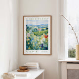 a framed poster of a countryside landscape with a flower market in Napa, California, hanging on a wall.