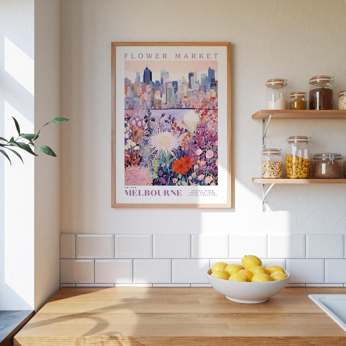 a kitchen counter with a bowl of lemons, a framed poster of Melbourne's flower market, and shelves with various jars and containers.
