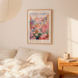 a bedroom setting with a framed poster of a flower market hanging on the wall above a bed with striped pillows.