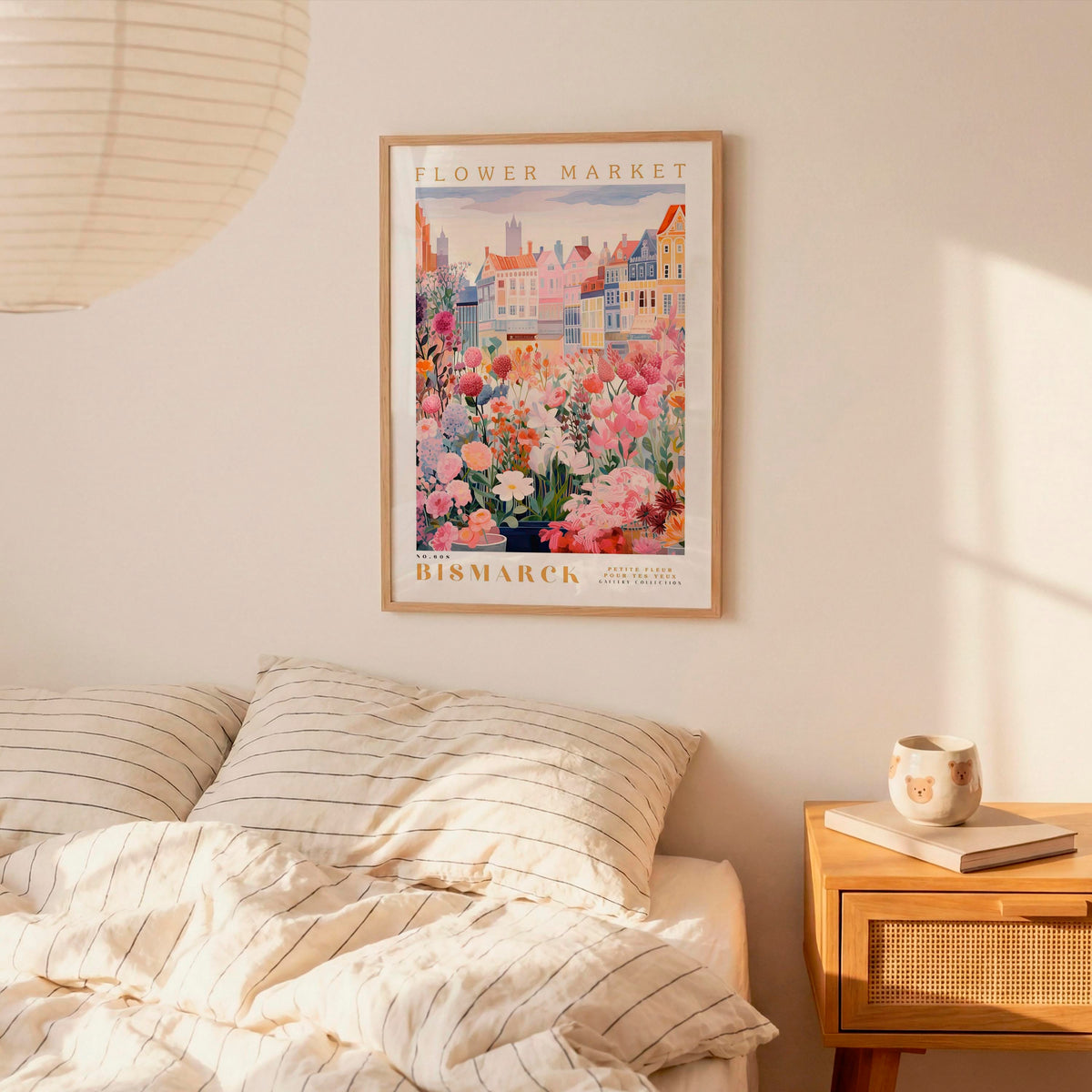 a bedroom setting with a framed poster of a flower market hanging on the wall above a bed with striped pillows.