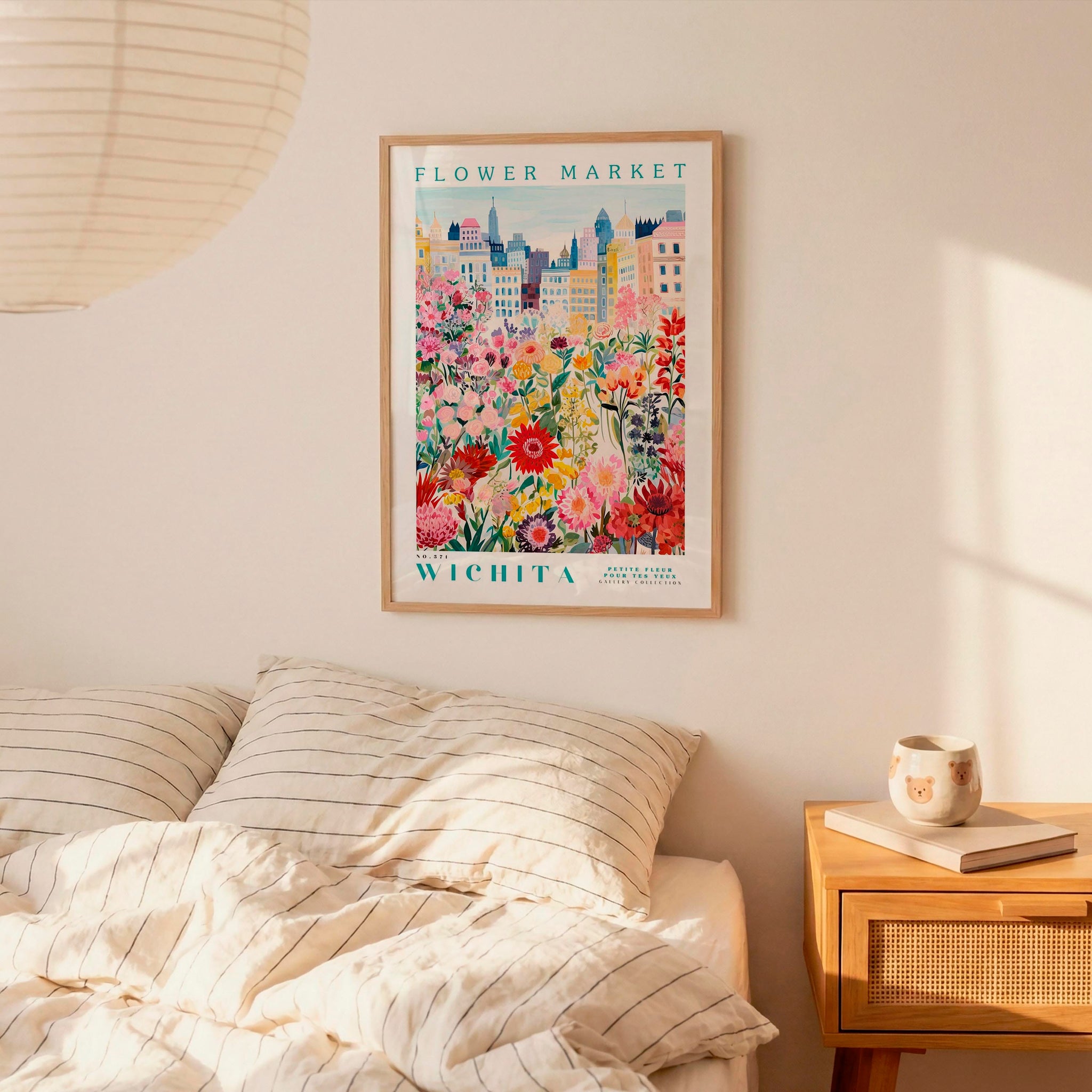 a bedroom setting with a framed poster of a flower market in Wichita, Kansas, hanging on the wall above a bed with striped pillows.