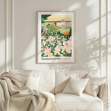 a framed poster of a garden with flowers hanging on a wall above a white couch with pillows.